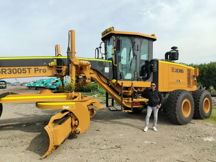Tezar Purwo R berdiri di samping unit motor grader